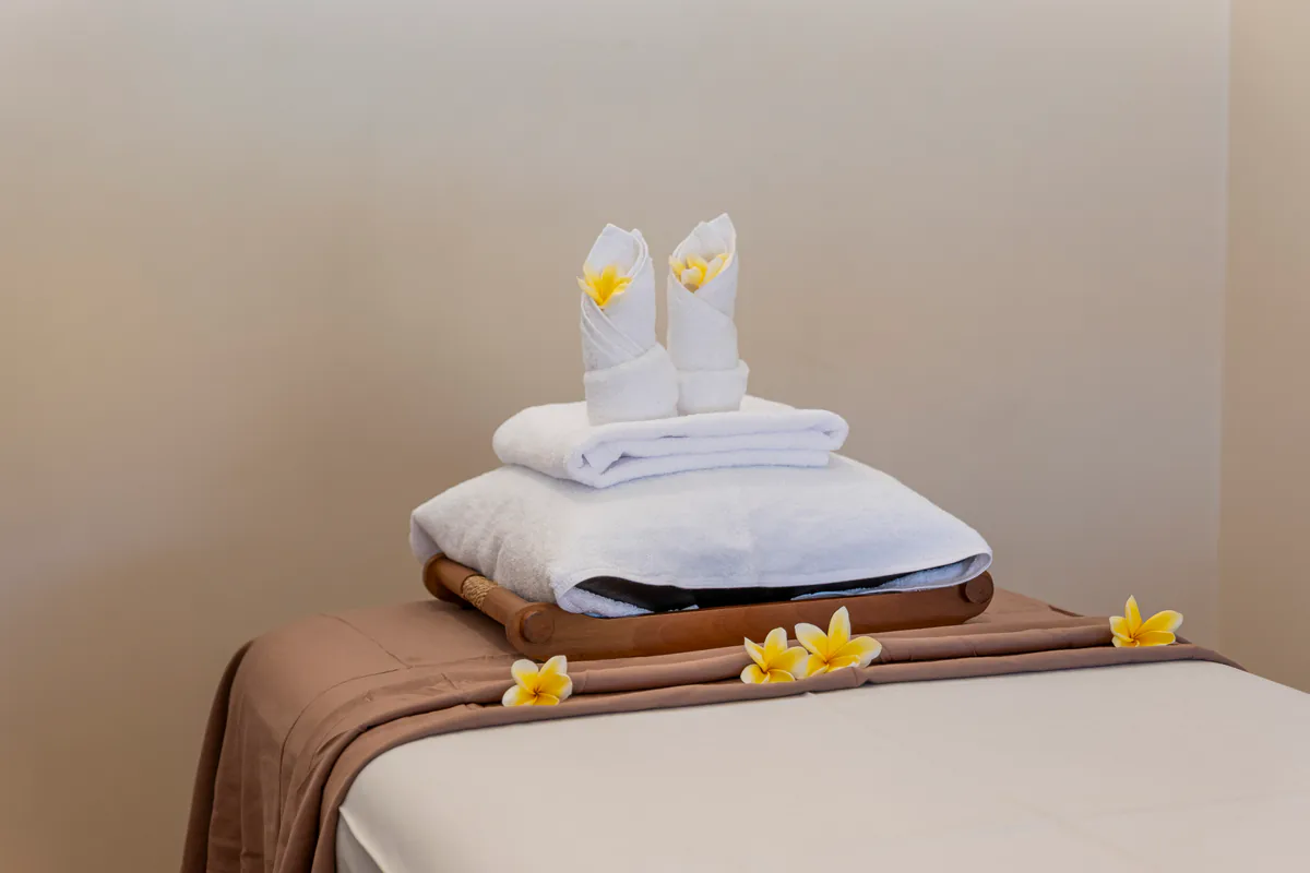 Massage table prepared with towels and frangipani at Sebayur Spa