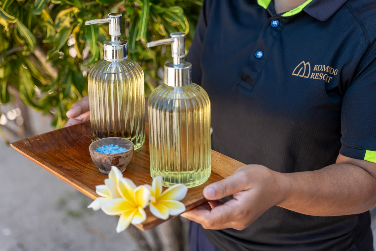 Spa therapist presenting massage oils and frangipani at Komodo Resort
